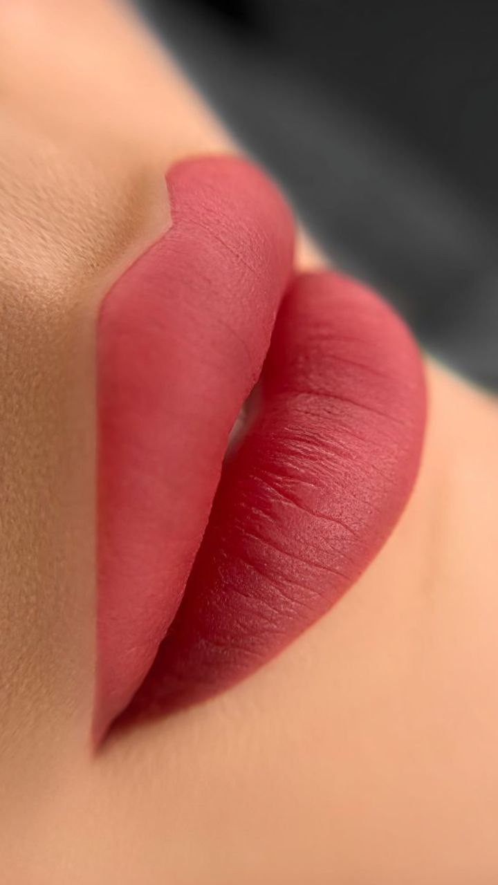 Close-up image showing a professional applying lip blush micropigmentation on a client’s lips. The procedure is performed with precision, enhancing the natural shape and color of the lips with semi-permanent pigment for a fuller, more defined look